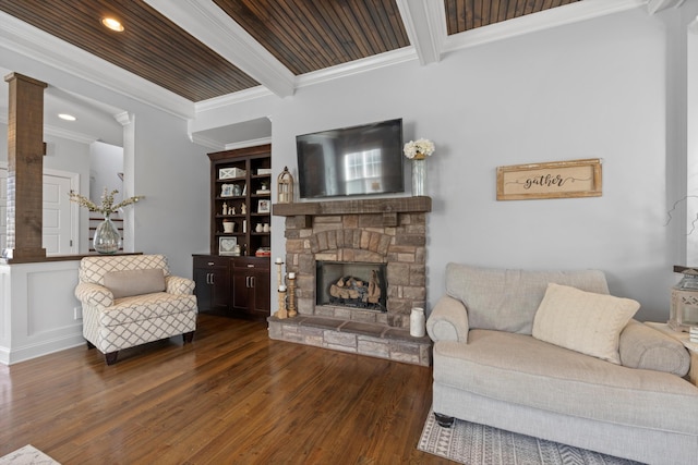 living room featuring dark wood-type flooring, a stone fireplace, crown molding, wooden ceiling, and beam ceiling