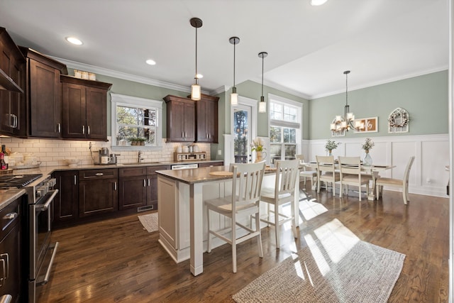 kitchen featuring a kitchen bar, sink, high end range, a center island, and pendant lighting