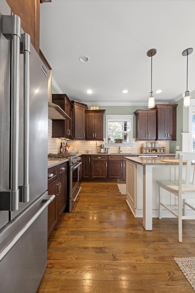 kitchen with pendant lighting, a breakfast bar area, backsplash, dark hardwood / wood-style flooring, and high end appliances