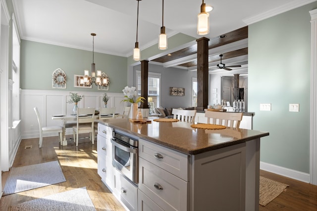 kitchen with pendant lighting, white cabinetry, a center island, crown molding, and light wood-type flooring