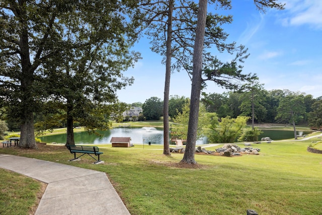 view of home's community with a water view and a lawn