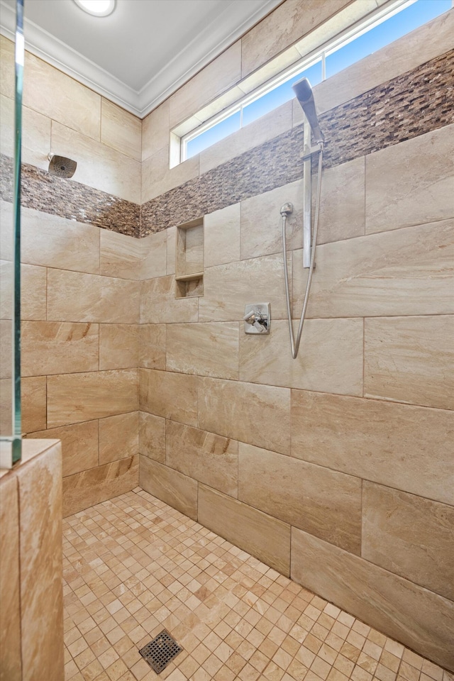 bathroom with ornamental molding and a tile shower