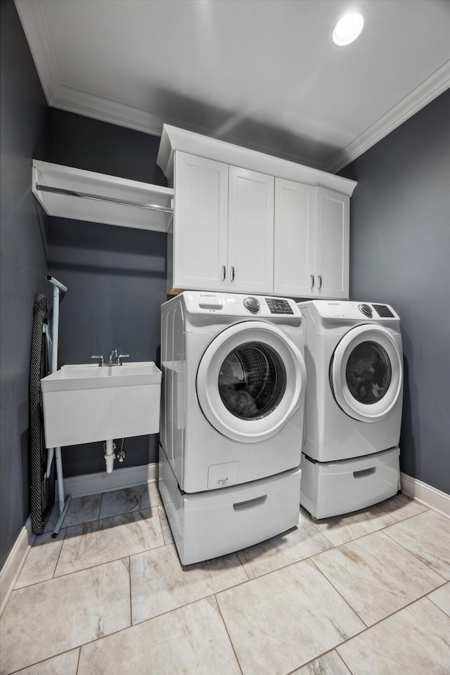 clothes washing area with cabinets, ornamental molding, sink, and washer and clothes dryer