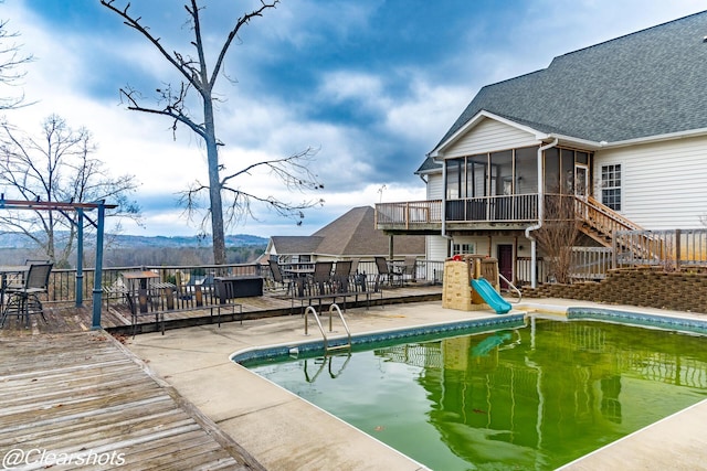 view of pool with a wooden deck and a sunroom