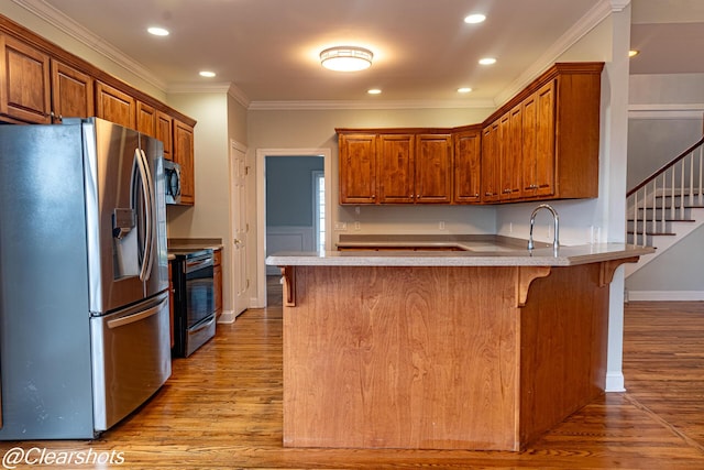 kitchen featuring stainless steel appliances, light wood-type flooring, a kitchen bar, and kitchen peninsula