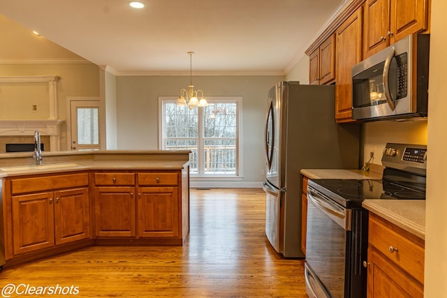 kitchen featuring appliances with stainless steel finishes, sink, a notable chandelier, crown molding, and light hardwood / wood-style flooring