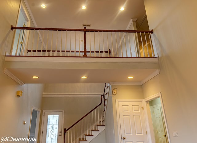 stairway with ornamental molding and a towering ceiling