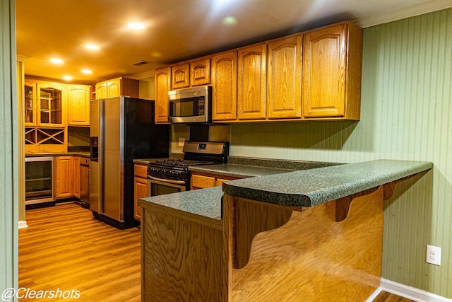 kitchen with beverage cooler, a kitchen bar, light hardwood / wood-style floors, kitchen peninsula, and stainless steel appliances