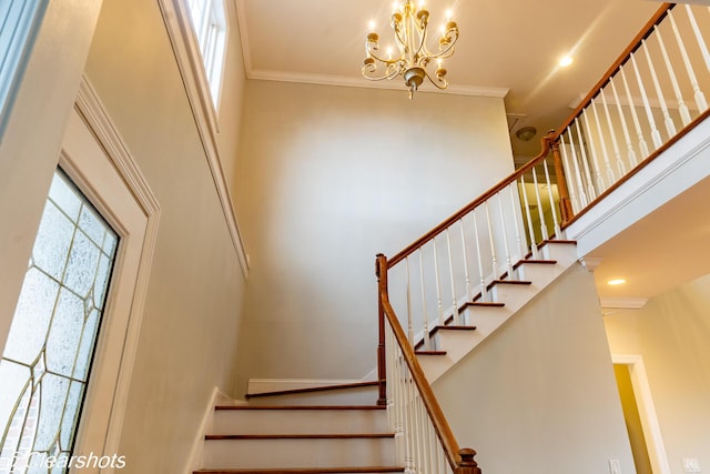 stairway with a towering ceiling, ornamental molding, a notable chandelier, and a wealth of natural light