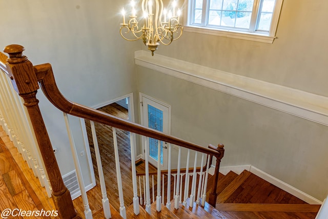 staircase with hardwood / wood-style flooring and a chandelier