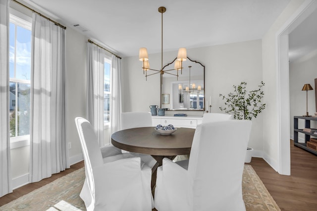 dining area featuring wood-type flooring and an inviting chandelier