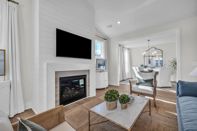 living room with hardwood / wood-style floors, an inviting chandelier, and vaulted ceiling