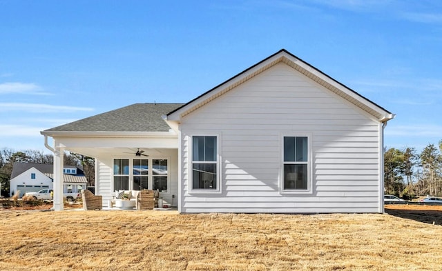 back of property featuring ceiling fan and a lawn