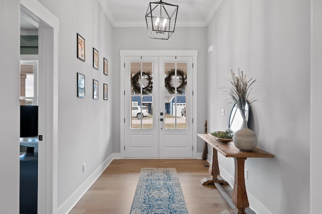 entryway featuring french doors, ornamental molding, light hardwood / wood-style floors, and an inviting chandelier