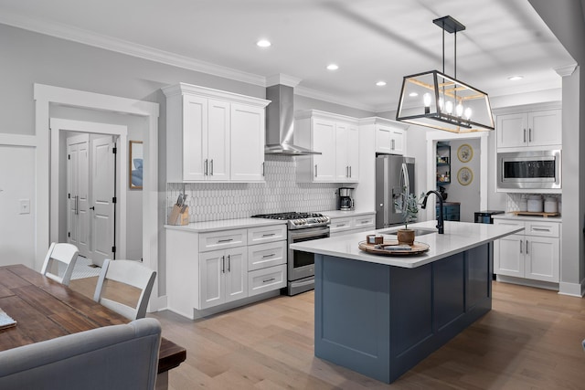 kitchen featuring pendant lighting, white cabinets, wall chimney range hood, decorative backsplash, and stainless steel appliances