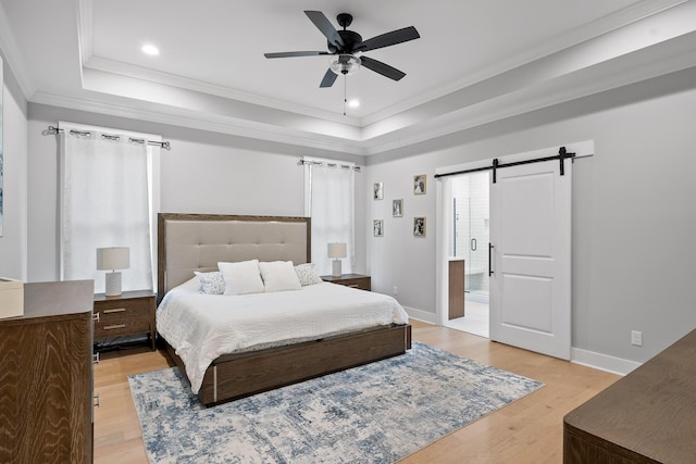 bedroom with ceiling fan, a raised ceiling, light wood-type flooring, a barn door, and ornamental molding