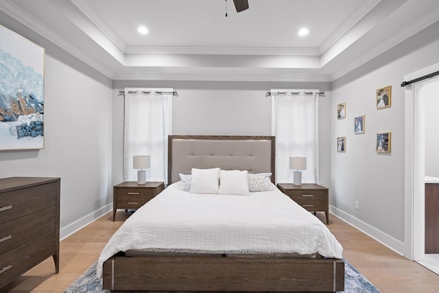 bedroom featuring ornamental molding, light hardwood / wood-style flooring, ceiling fan, and a raised ceiling