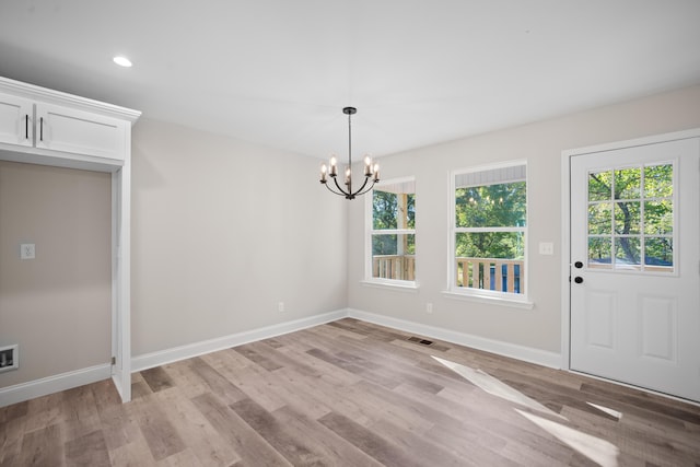 unfurnished dining area featuring light wood-type flooring and an inviting chandelier