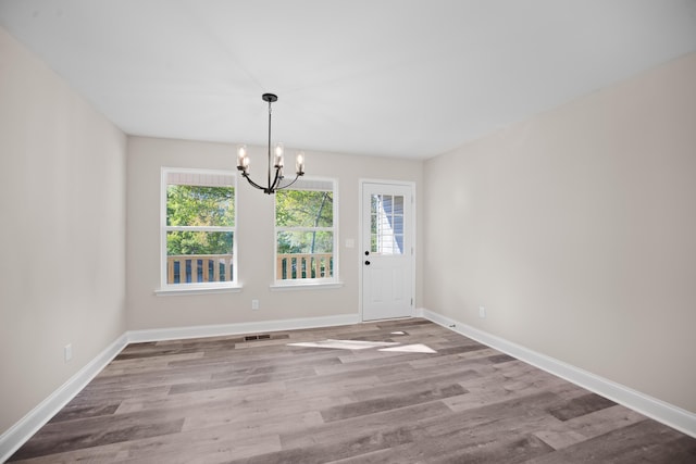 unfurnished dining area featuring hardwood / wood-style flooring and a notable chandelier