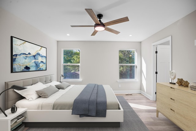 bedroom with ceiling fan, multiple windows, and light wood-type flooring