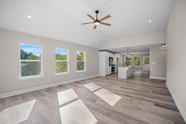 unfurnished living room with ceiling fan with notable chandelier, sink, light hardwood / wood-style flooring, and lofted ceiling