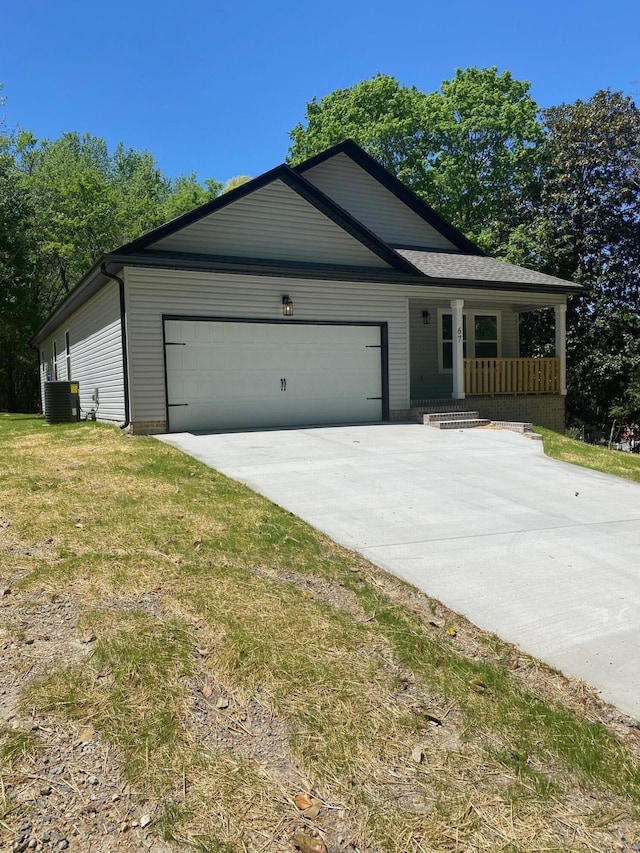 view of front of house featuring a front yard, an attached garage, covered porch, and concrete driveway