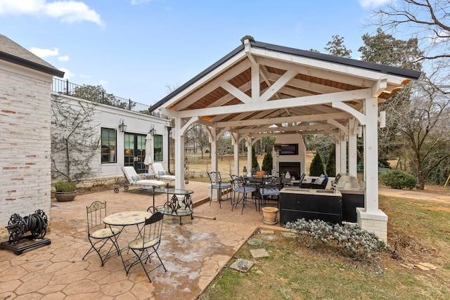 view of patio featuring exterior fireplace and a gazebo