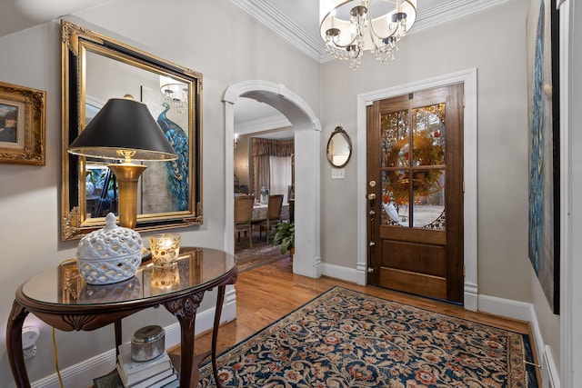 foyer entrance with hardwood / wood-style flooring, crown molding, and an inviting chandelier