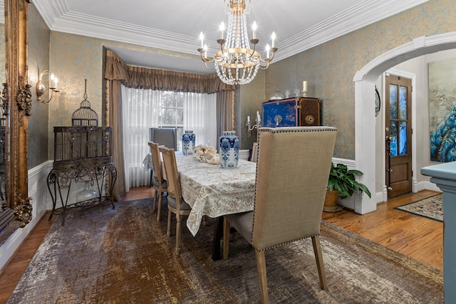 dining area with wood-type flooring, crown molding, and an inviting chandelier