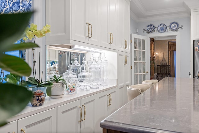 bar featuring white cabinets and ornamental molding