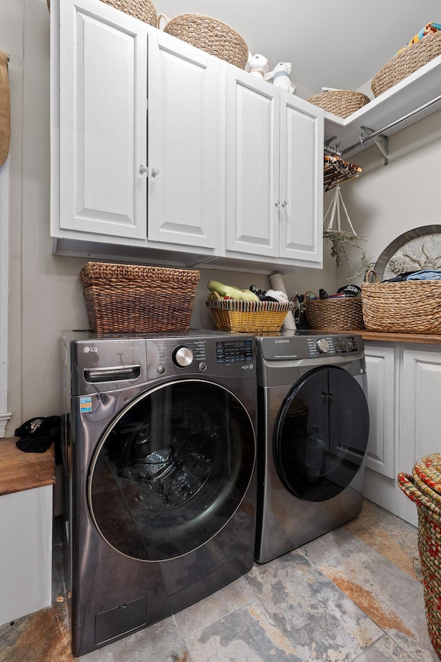 clothes washing area featuring washer and dryer and cabinets