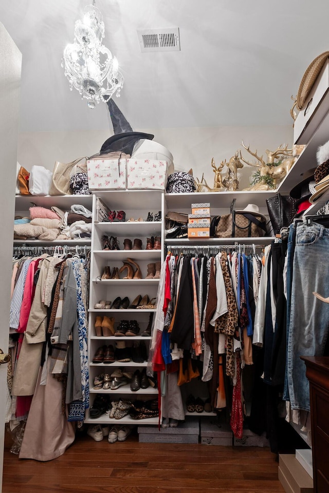 walk in closet featuring hardwood / wood-style flooring and an inviting chandelier