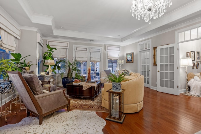 living room featuring hardwood / wood-style floors, a tray ceiling, crown molding, and a chandelier