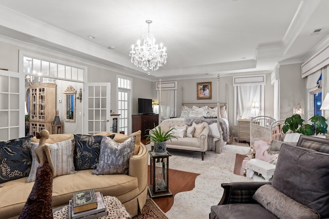 bedroom featuring hardwood / wood-style flooring, ornamental molding, a raised ceiling, and a notable chandelier