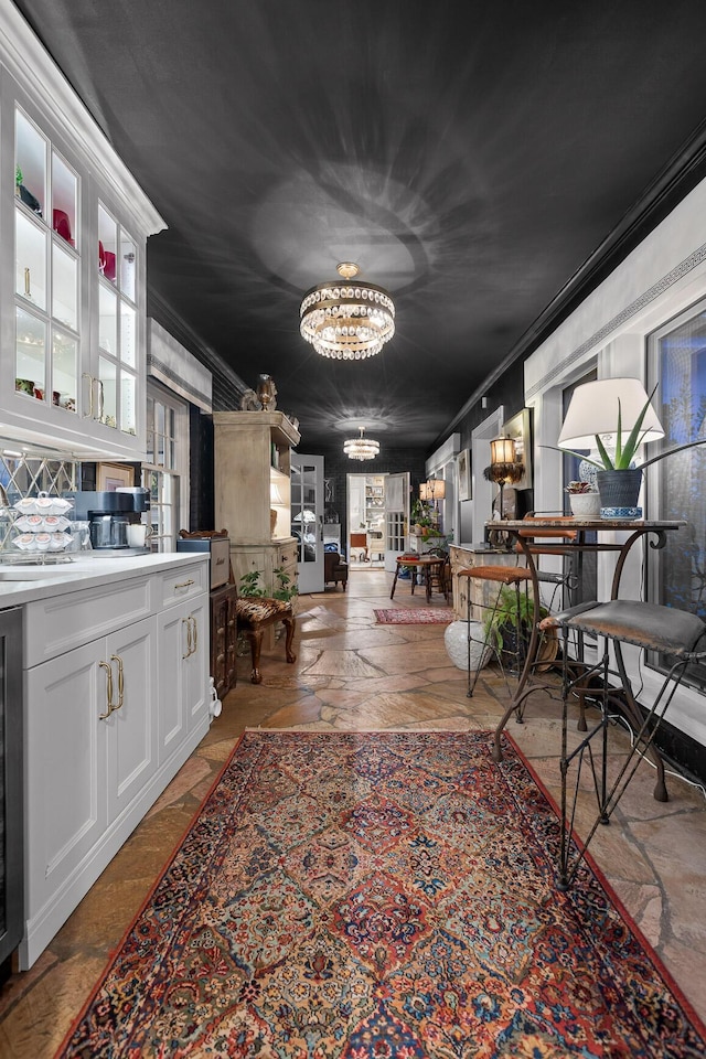 dining area with a chandelier, crown molding, and wine cooler