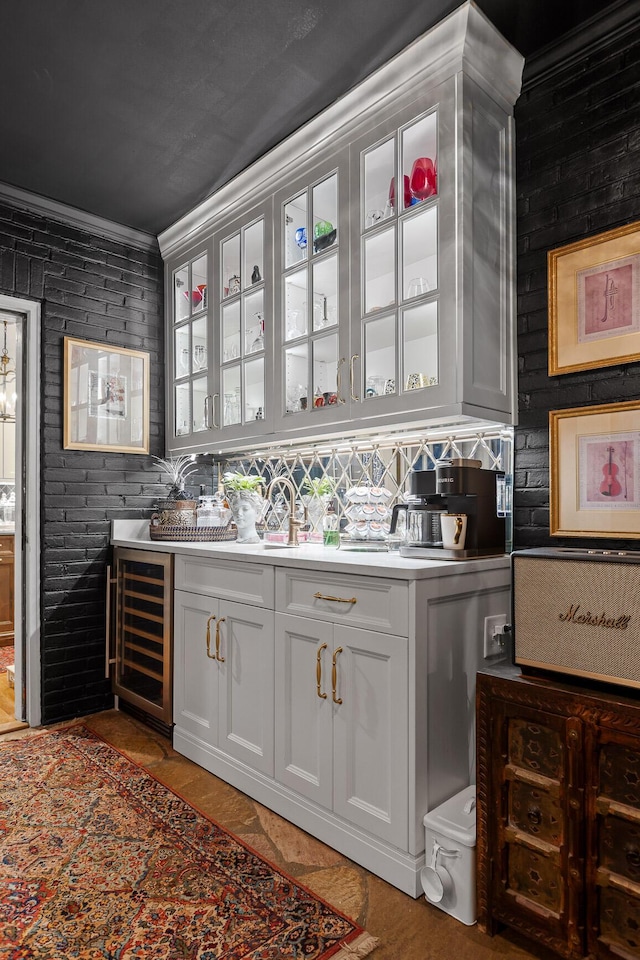 bar with white cabinets, brick wall, crown molding, and beverage cooler