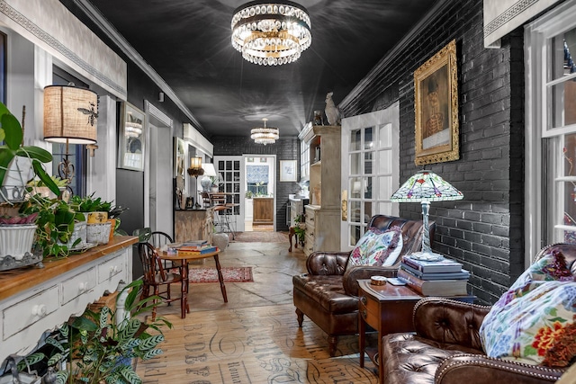 interior space with brick wall, ornamental molding, and a notable chandelier