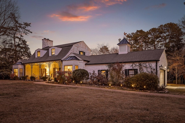 view of front of property featuring a garage, a yard, and covered porch