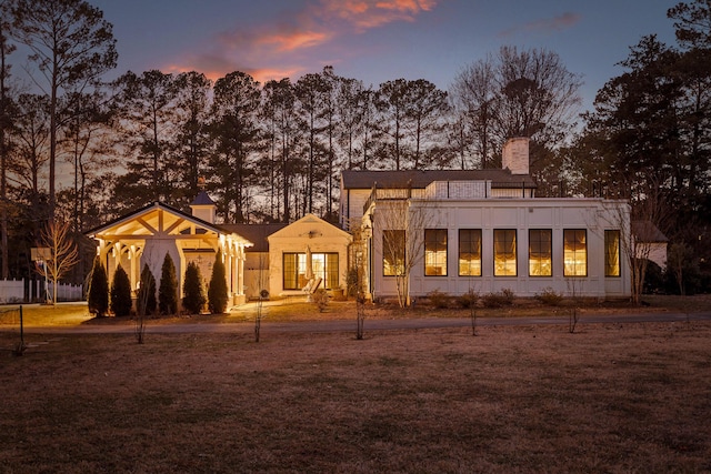 back house at dusk with a lawn