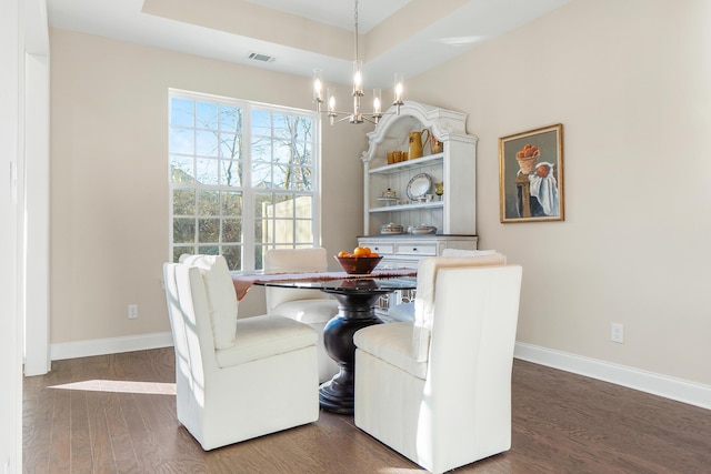 dining area featuring a tray ceiling, dark hardwood / wood-style floors, and a chandelier