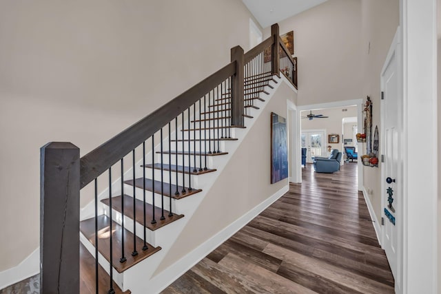 stairway with a towering ceiling and wood-type flooring