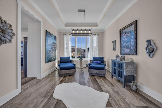 living area featuring a raised ceiling, ornamental molding, and hardwood / wood-style floors