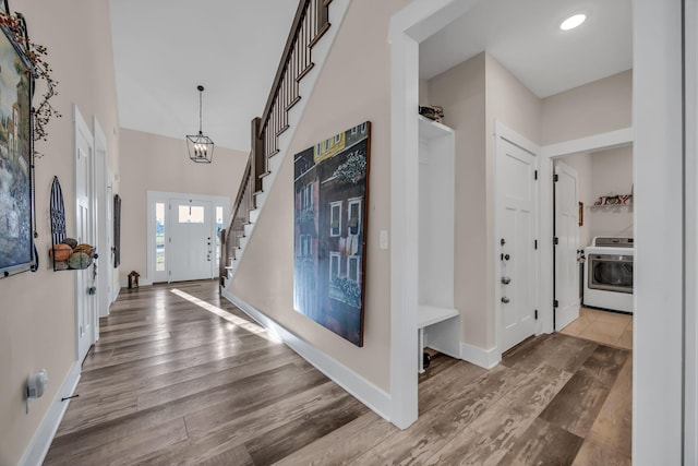 foyer entrance with washer / clothes dryer, hardwood / wood-style floors, and a notable chandelier