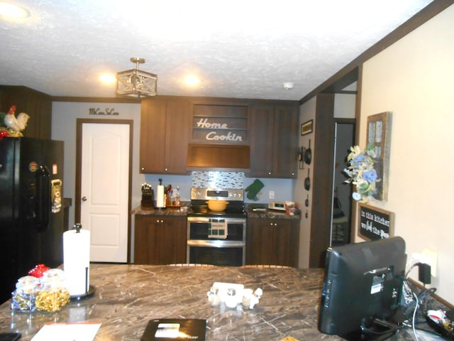 kitchen with range with two ovens, a textured ceiling, black refrigerator, ornamental molding, and decorative backsplash