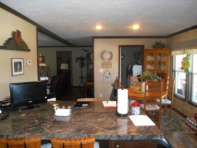 dining space featuring ornamental molding, dark wood-type flooring, and a textured ceiling