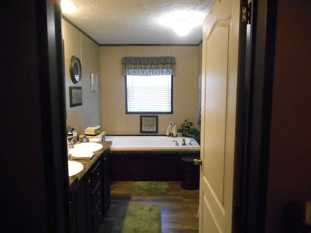 bathroom with a tub, hardwood / wood-style flooring, vanity, crown molding, and a textured ceiling