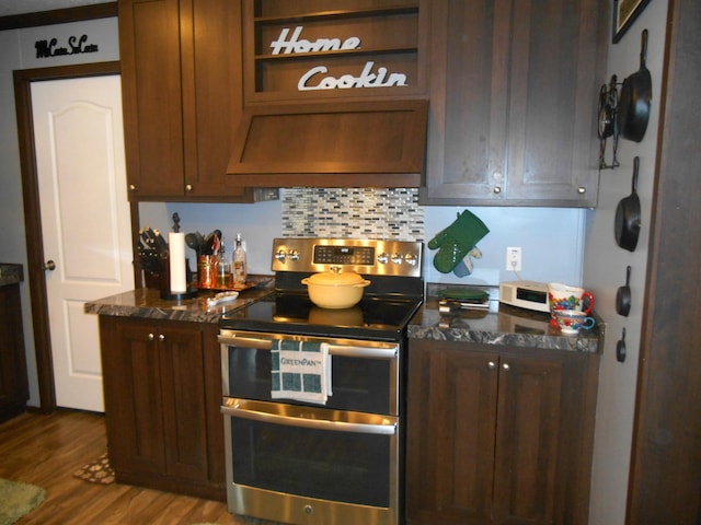 kitchen with hardwood / wood-style floors, backsplash, dark stone counters, range with two ovens, and custom range hood