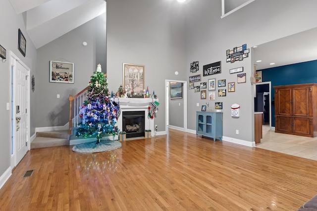 unfurnished living room with light wood-type flooring and high vaulted ceiling