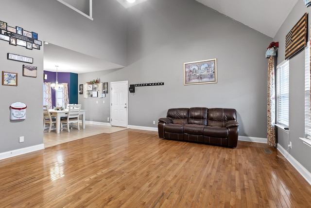 living room featuring high vaulted ceiling, wood-type flooring, and a chandelier