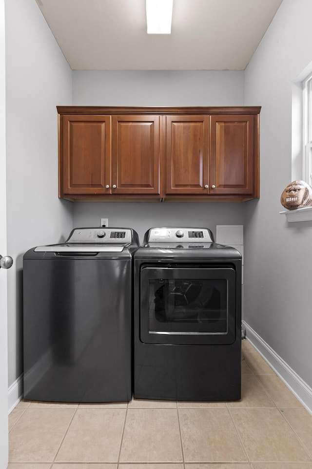 laundry room featuring washer and dryer, cabinets, and light tile patterned flooring